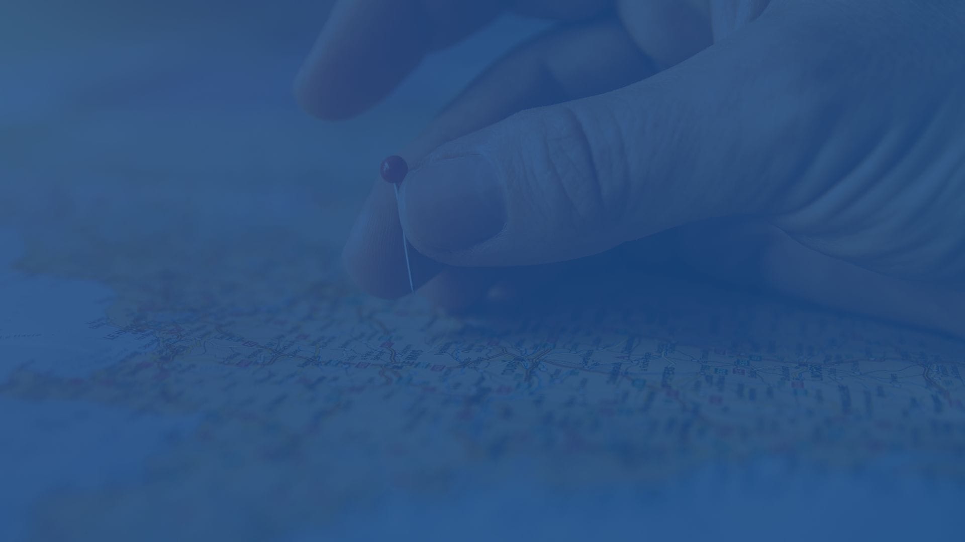 Hand placing a pin on a map to mark a specific location in Europe, symbolizing travel planning or destination marking.