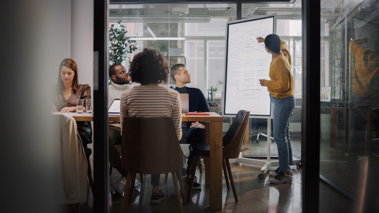Team meeting in a modern office with a presenter at a flip chart discussing ideas and strategies.