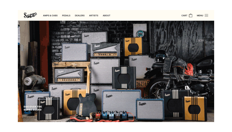 Display of various guitar amplifiers stacked, with a guitar and foot pedals in front, set against a dark backdrop.